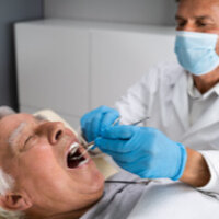 elderly man having his dentures inspected by a denturist