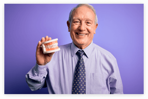 Patient Holding Their Dentures smiling elderly man in a dress shirt and tie holding a denture model