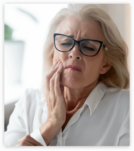 older woman holding her face because of tooth pain.