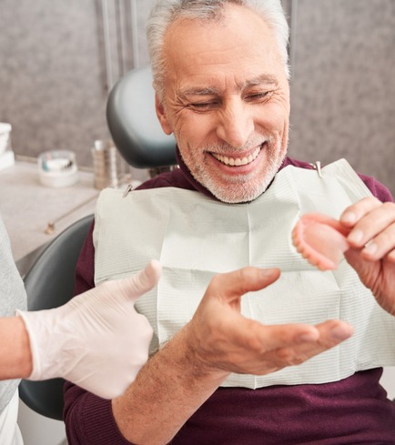 Patient Holding Dentures a man holding implant supported dentures