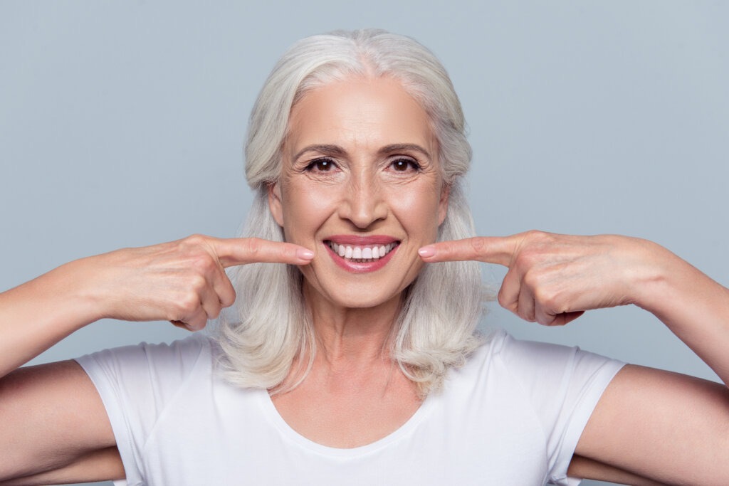 a woman smiling with her implant supported dentures