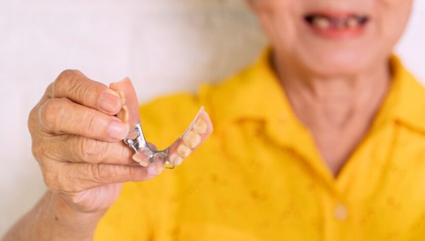 elderly person holding their dentures in their hand