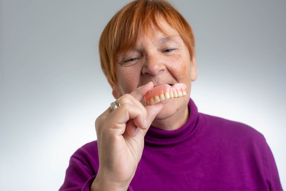 woman holding her new dentures in front of her mouth