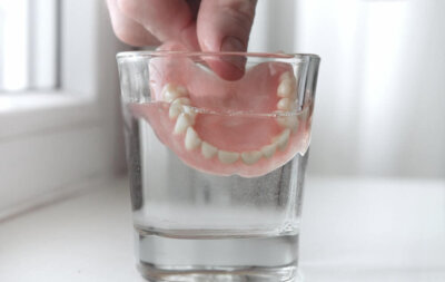 Soaking Dentures Hand Dipping Dentures In Cup of Water