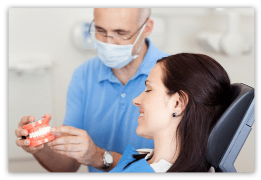 Denturist showing a patient a model of teeth during appointment
