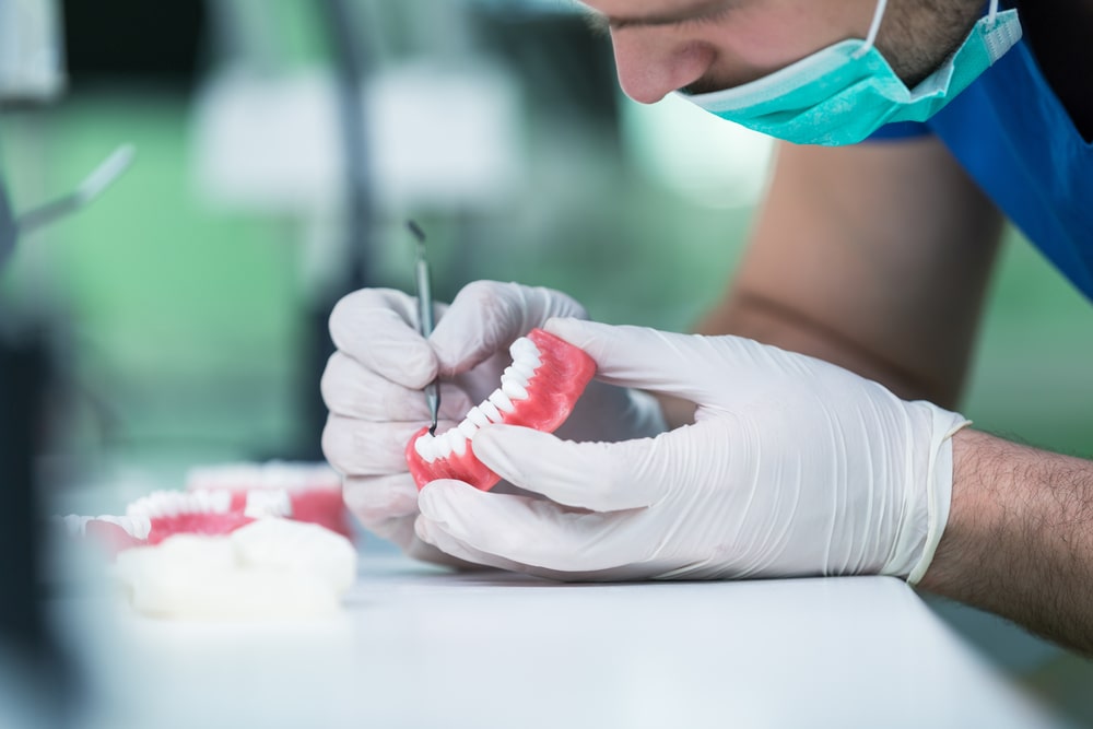 A denturist maintaining a set of dentures. 