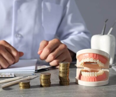 a set of dentures next to a stack of coins.
