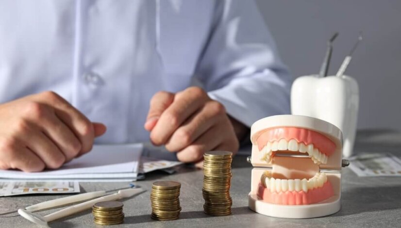 a set of dentures next to a stack of coins.